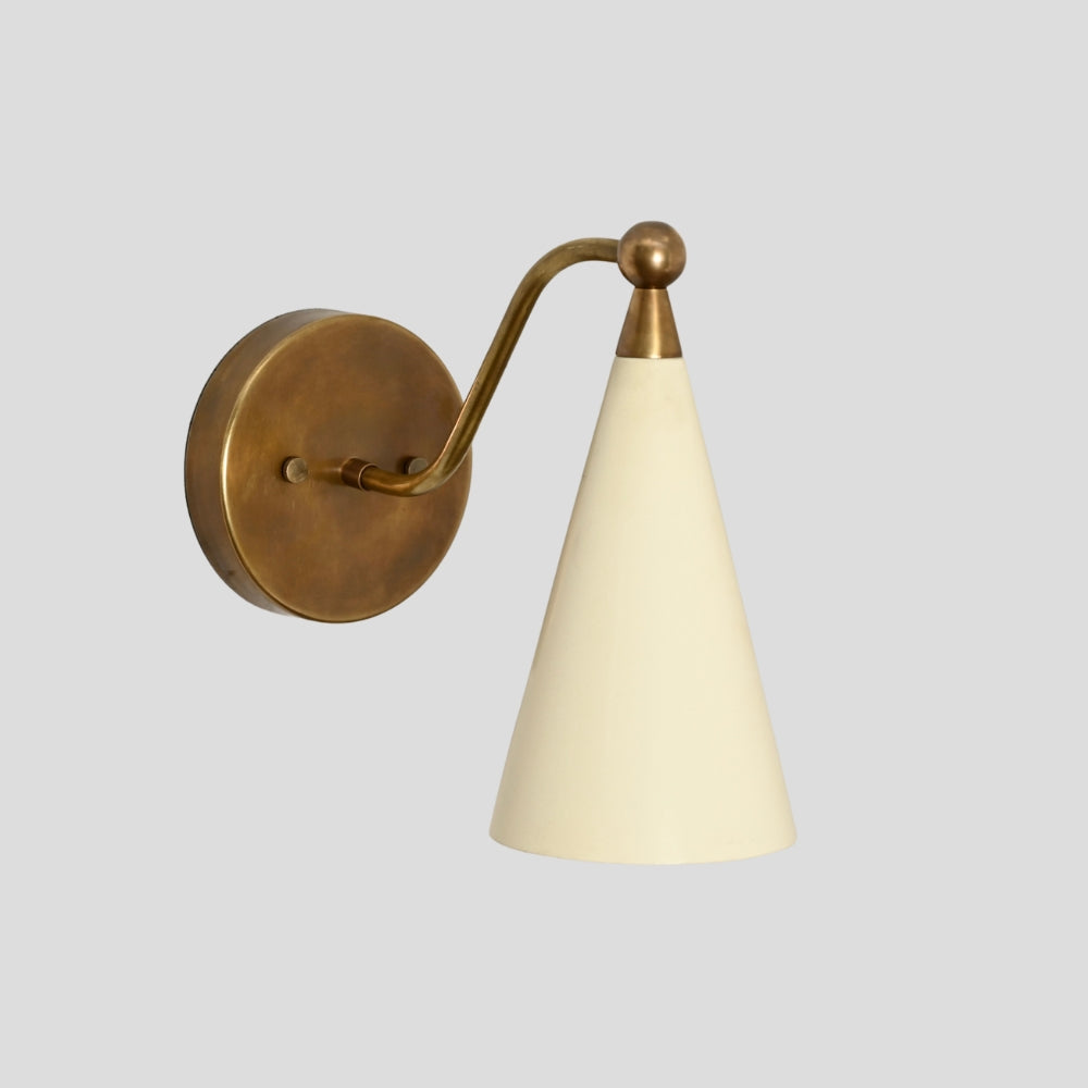 Modern mid century wall sconce in brass with cream cone shade.