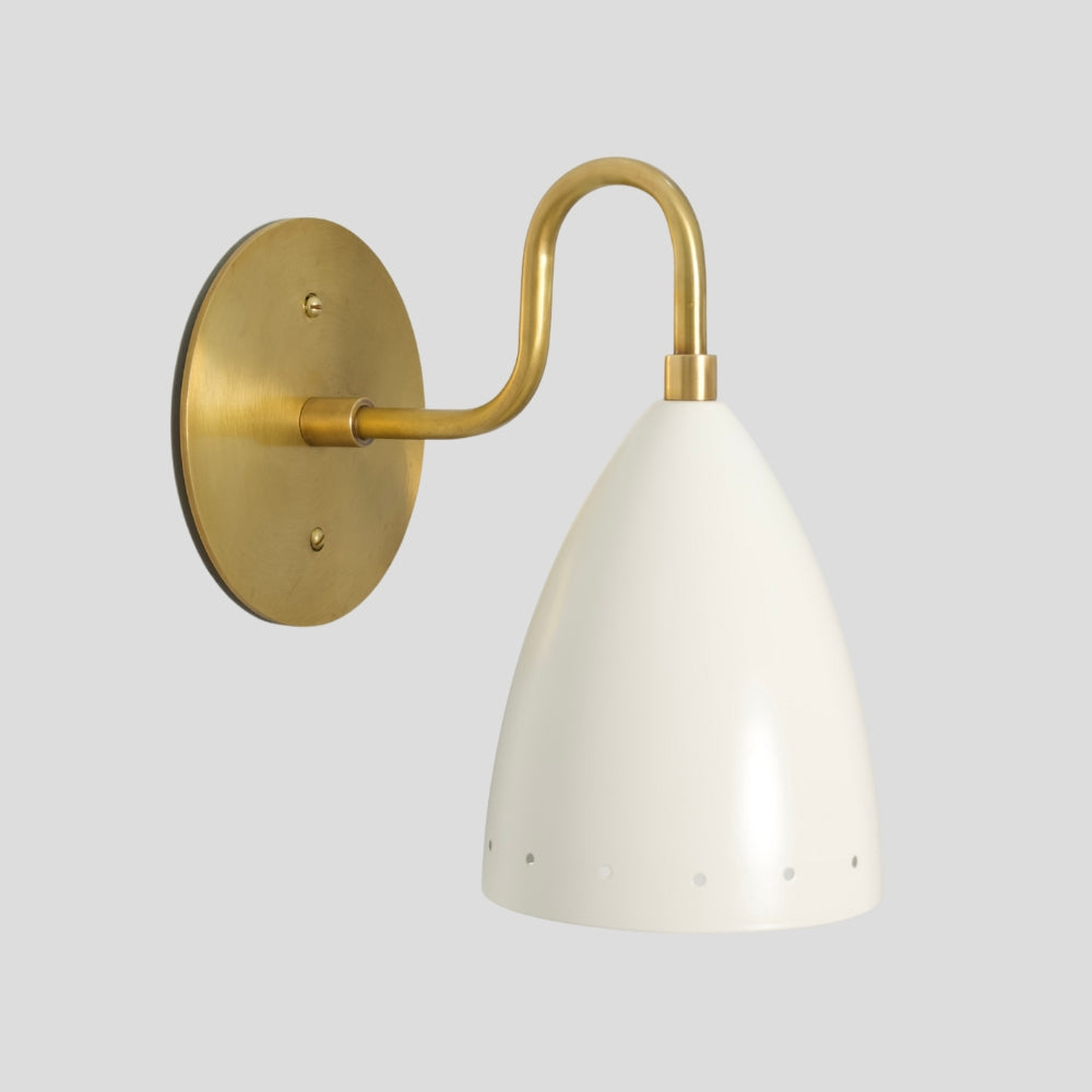 Brass wall light with white perforated shade creating soft warm ambient lighting for living room or bedside.