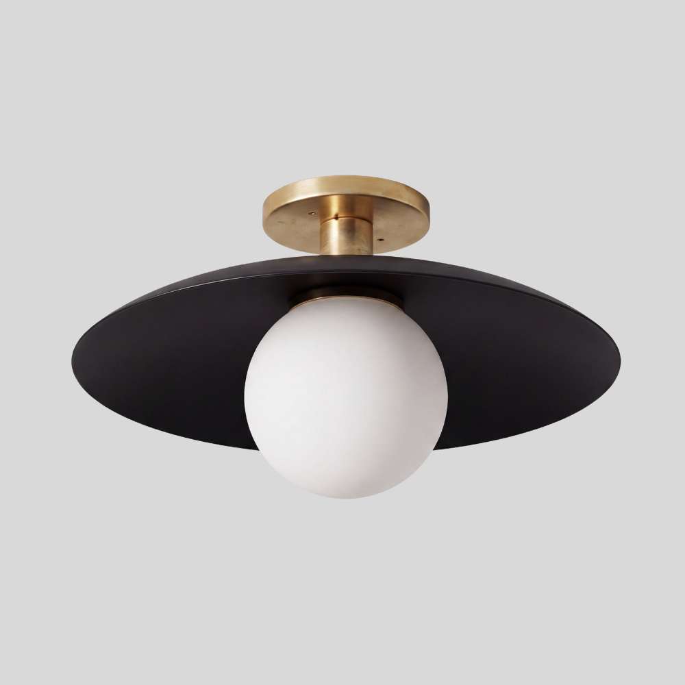 Black and brass flush mount ceiling light featuring a spherical glass globe shade and a brass canopy, designed in a mid-century modern style with a matte black finish.