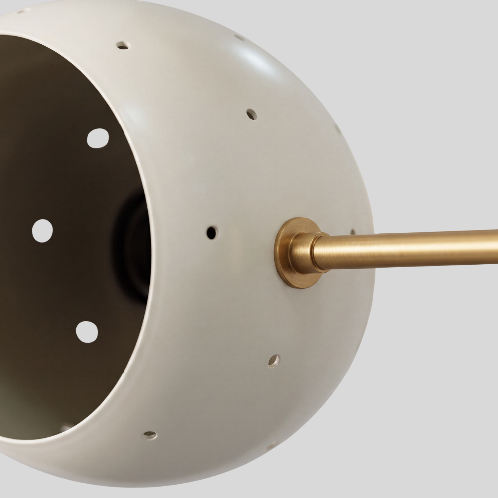 Triple white orb ceiling light featuring three perforated globe shades on a raw brass semi-flush mount, with a mid-century modern aesthetic and ambient pinhole lighting details.