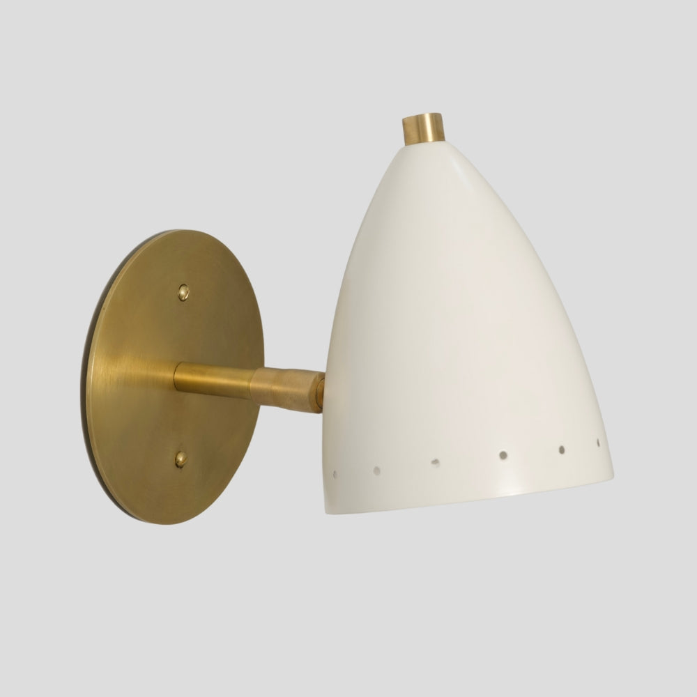 Wall-mounted light fixture with white shade and brass metal arm on a light gray background