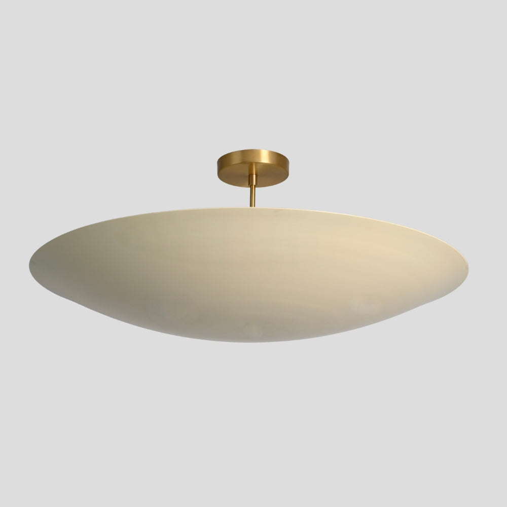 Ceiling light fixture with gold fixture and white shade on a gray background