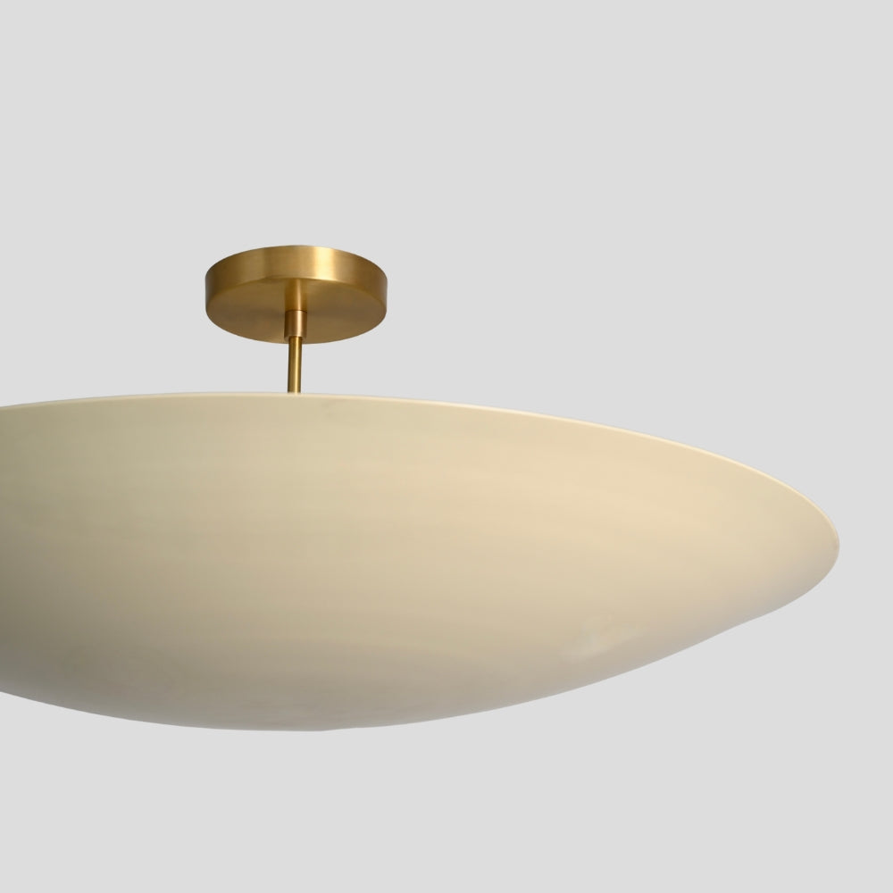 Ceiling light fixture with gold finish and beige shade on a gray background