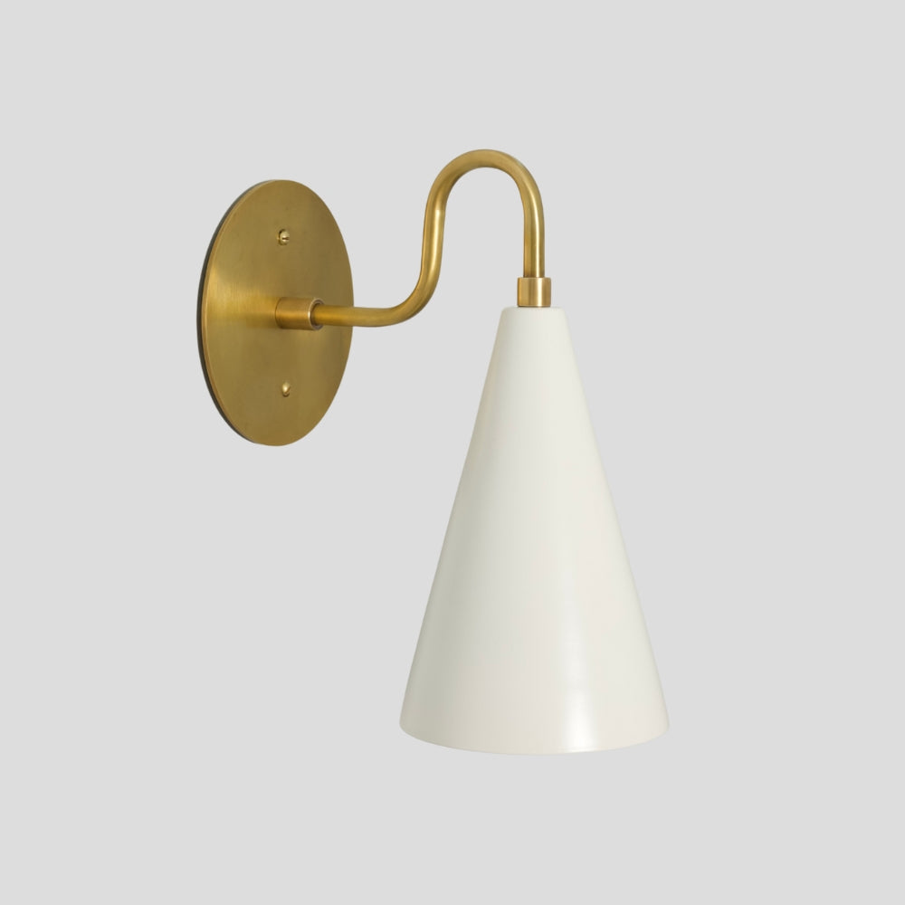Minimalist brass wall sconce with white cone shade, ideal for layered lighting in small spaces.