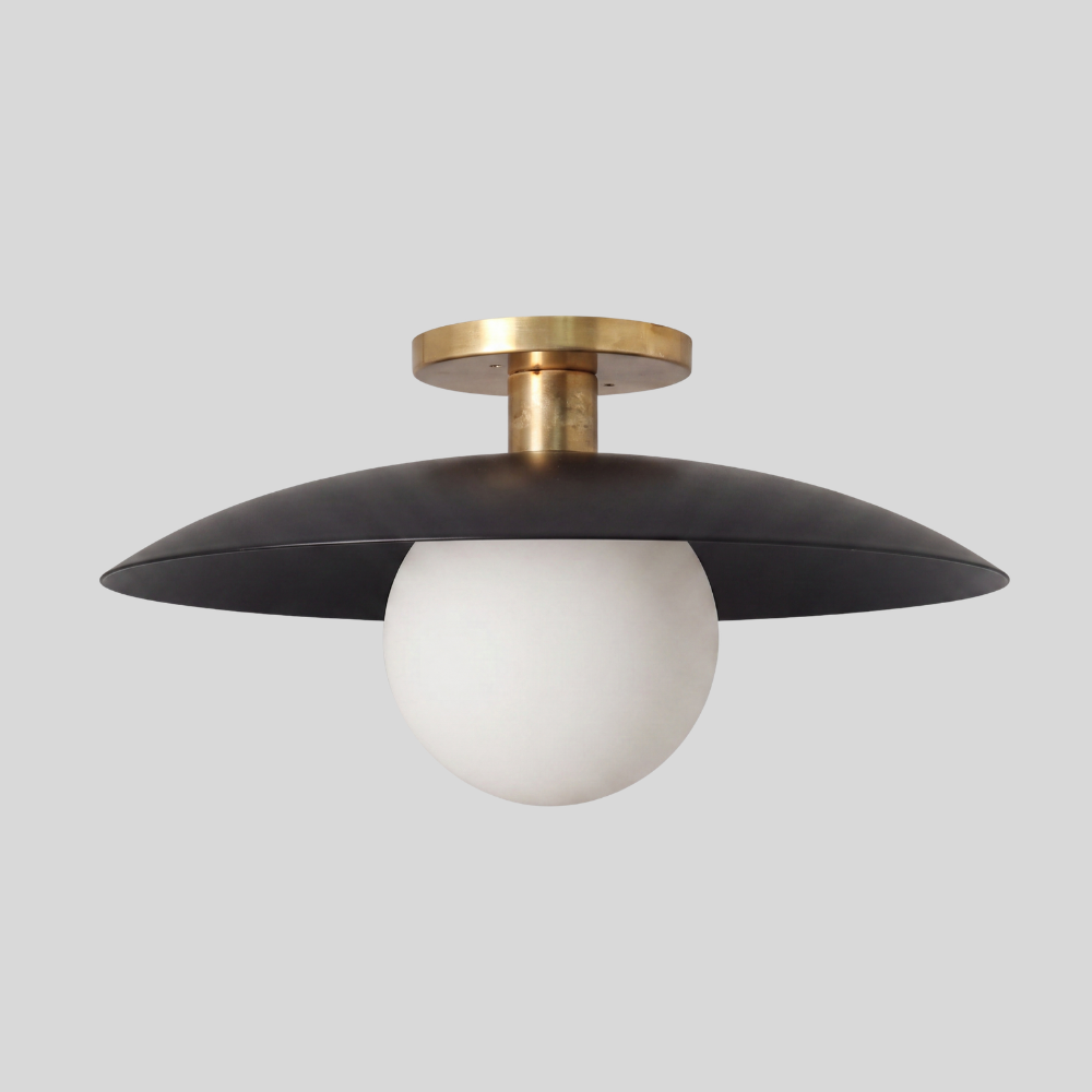 Black and brass flush mount ceiling light featuring a spherical glass globe shade and a brass canopy, designed in a mid-century modern style with a matte black finish.