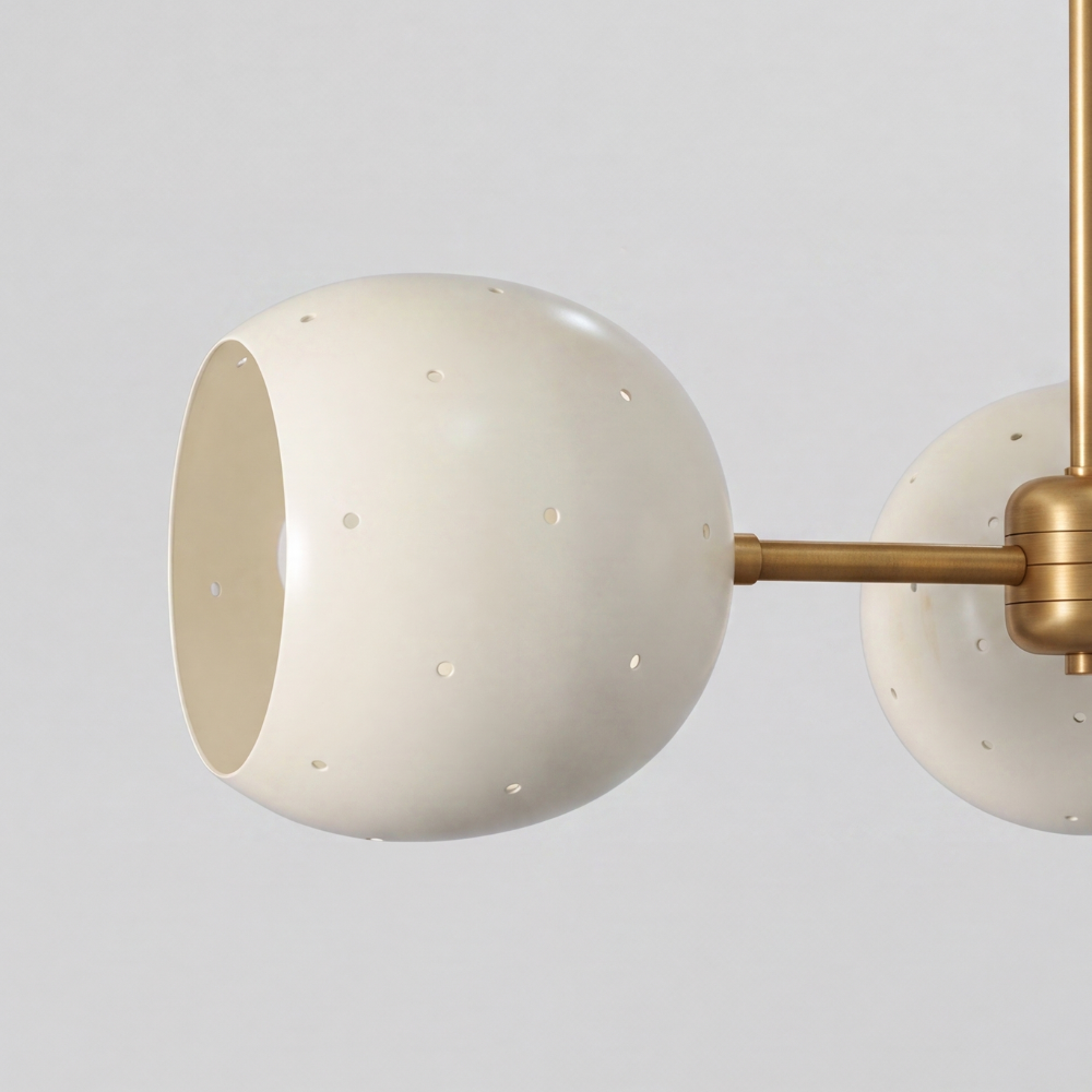 Triple white orb ceiling light featuring three perforated globe shades on a raw brass semi-flush mount, with a mid-century modern aesthetic and ambient pinhole lighting details.