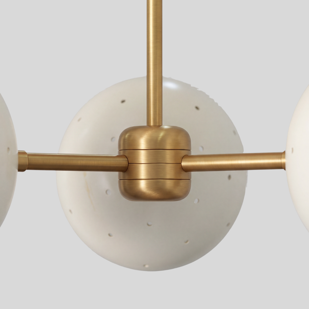 Triple white orb ceiling light featuring three perforated globe shades on a raw brass semi-flush mount, with a mid-century modern aesthetic and ambient pinhole lighting details.